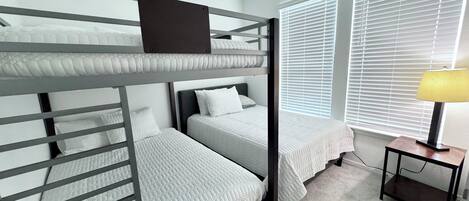 A bunk bed room with a desk and lamp.