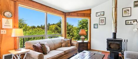 A cozy room with a sofa, a table, a lamp, a fireplace, and a view of the outdoors.