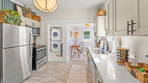 A modern kitchen with stainless steel appliances, a dining area with a table and chairs, and a laundry room with stacked washing machines.