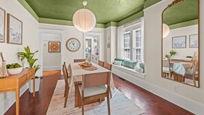 A dining area with a wooden table and chairs, a large mirror, and a window with a view.