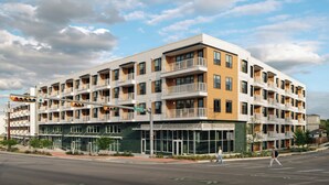 A multi-story hotel with balconies, large windows, and a green facade.