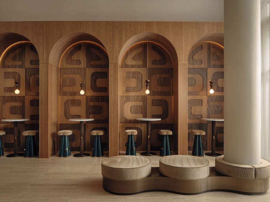 A modern interior with wooden walls, arched niches, round tables, and stools.