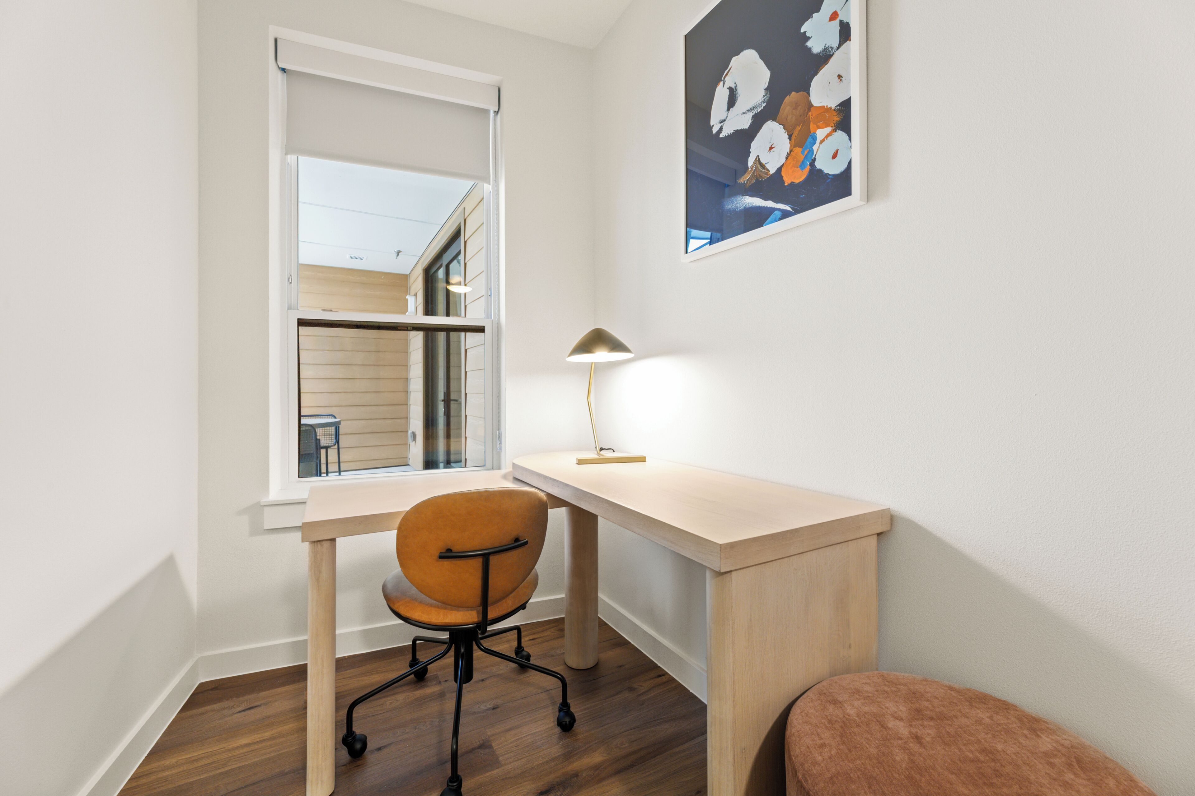 Una habitación con escritorio, silla y ventana.