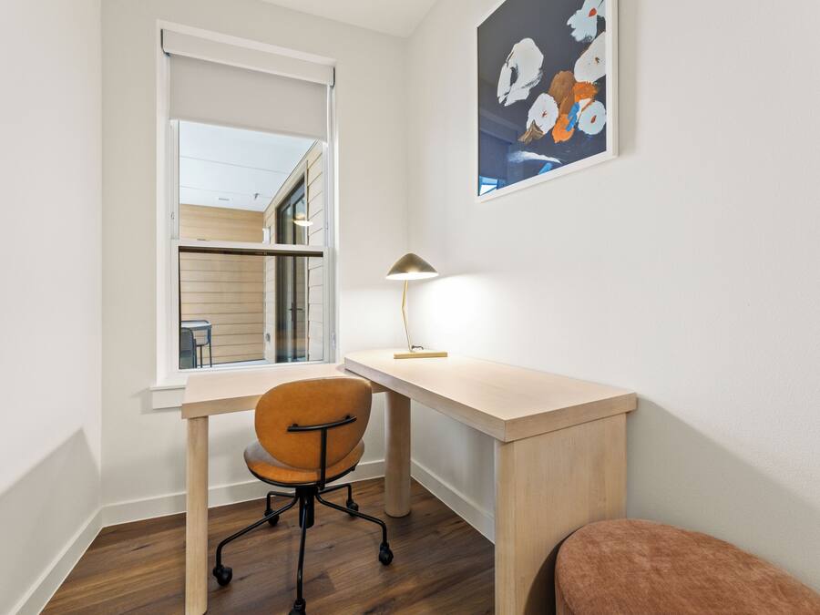 Una habitación con escritorio, silla y ventana.