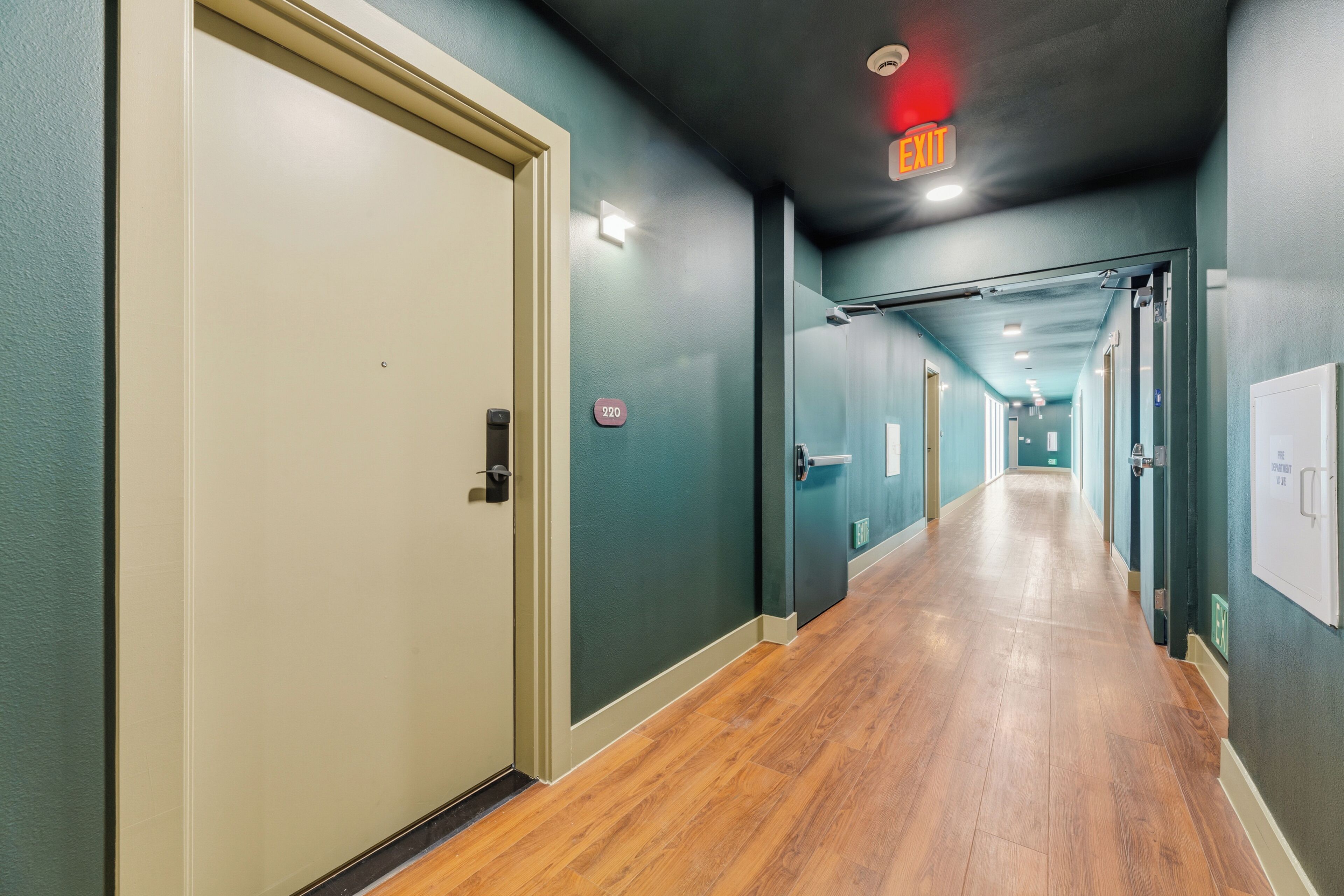 A hallway with a door, a sign, and a light fixture.