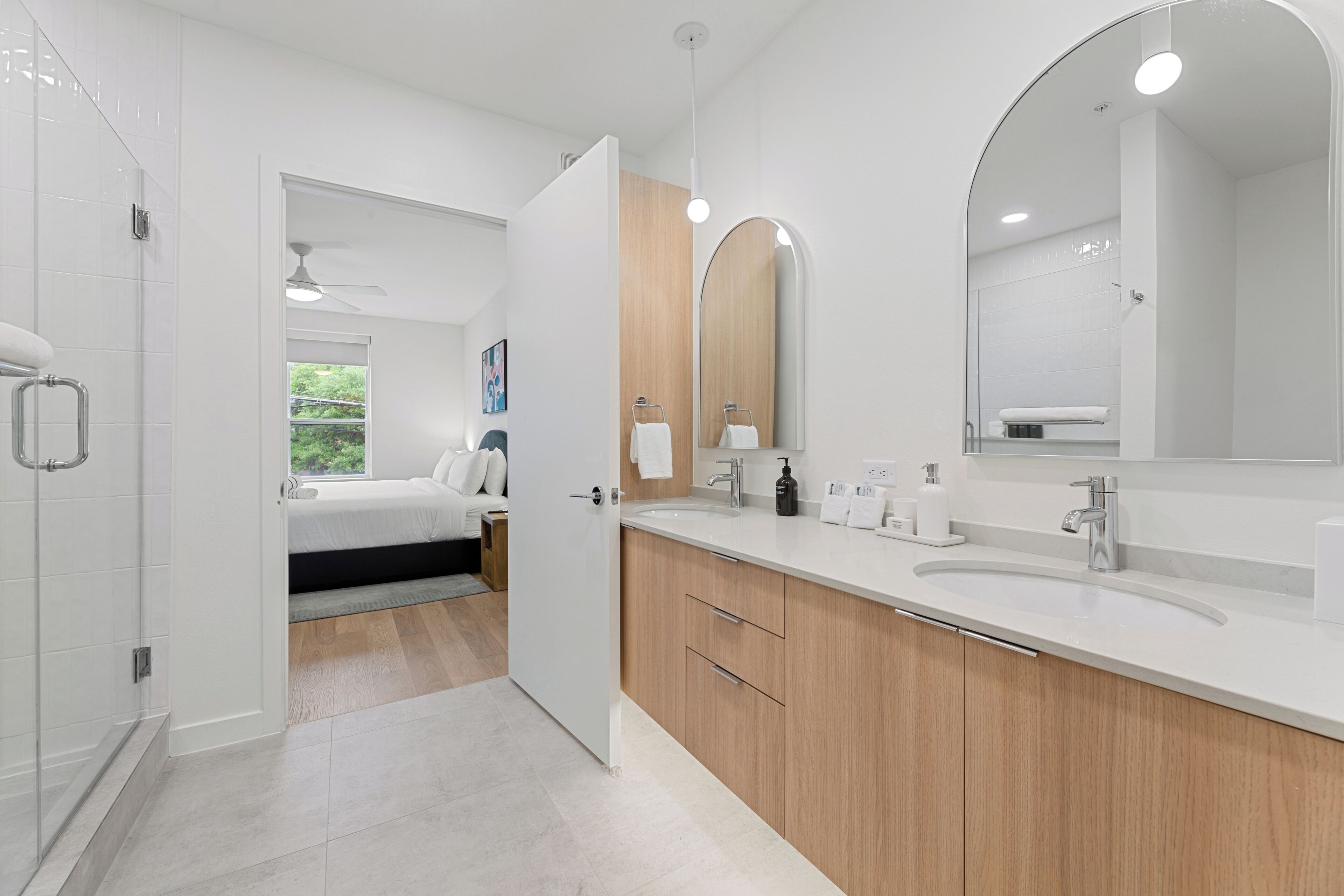 A modern bathroom with a large mirror, a shower, and a sink.
