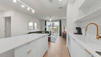A modern kitchen with white cabinetry, a central island, and a large window.