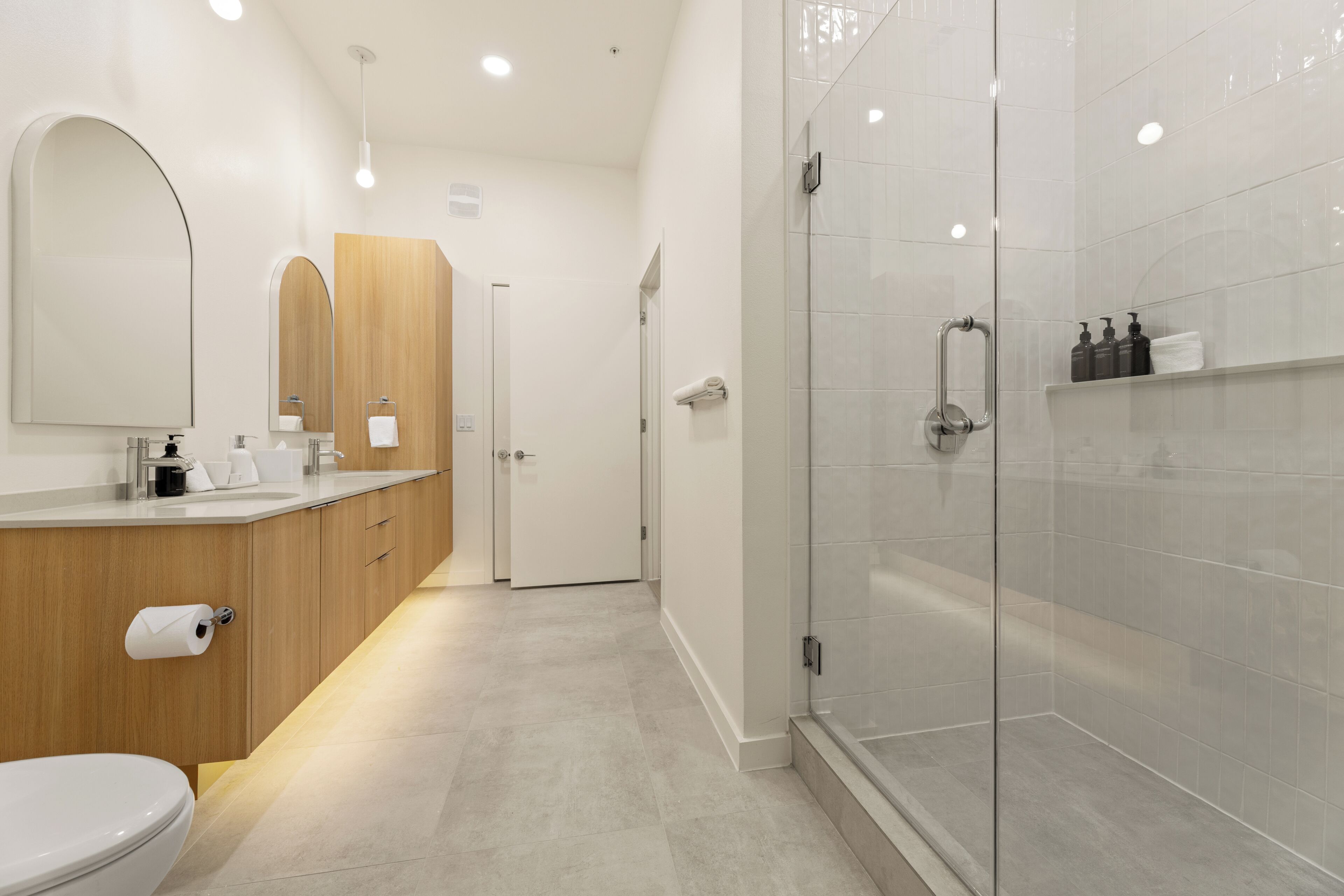 Un bagno moderno con WC, lavandino, specchio, doccia e cabina doccia in vetro.