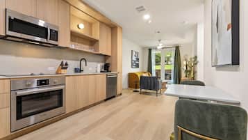 A modern kitchen with stainless steel appliances, wooden cabinets, and a dining area with a table and chairs.