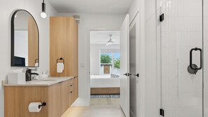 Une salle de bain moderne avec un meuble-lavabo en bois, un grand miroir et une cabine de douche en verre.