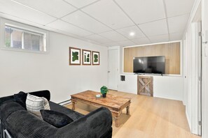 Un salon moderne avec un canapé, une table basse et un téléviseur fixé au mur, qui est en bois.