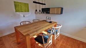 Ein Essbereich mit Holztisch und Stühlen, einer Pendelleuchte und einem an der Wand befestigten Schrank.
