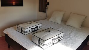 Ein Bett mit zwei weißen Matratzen, zwei weißen Kissen, einer Wandleuchte und einem Sonnenuntergangsbild.