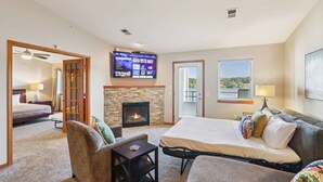 A hotel room with a bed, a sofa, a TV mounted on the wall, a fireplace, and a balcony door. - Jana`s Penthouse, Fireplace, Skiing, Boating (Wisconsin Dells)