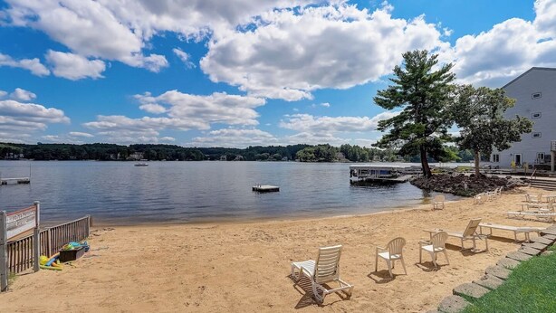 A beach with a dock and lounge chairs, a pier, and a building with a dock. - Jana`s Penthouse, Fireplace, Skiing, Boating (Wisconsin Dells)