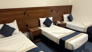 A hotel room with two beds, a wooden headboard, and a blue carpet.