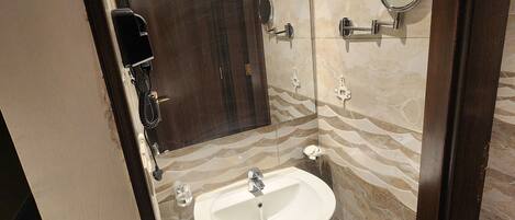 A bathroom with a marble wall, a sink, a mirror, and a hairdryer.