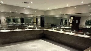 A modern bathroom with multiple sinks, a large mirror, and recessed lighting.