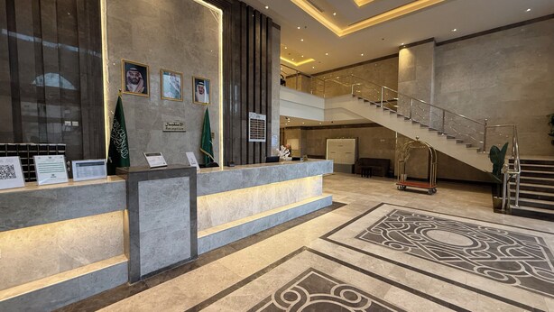 A reception area with a marble counter, framed portraits, flags, and a staircase.