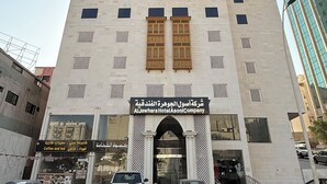 A tall hotel with a modern facade, featuring a large entrance with a decorative archway and multiple windows.