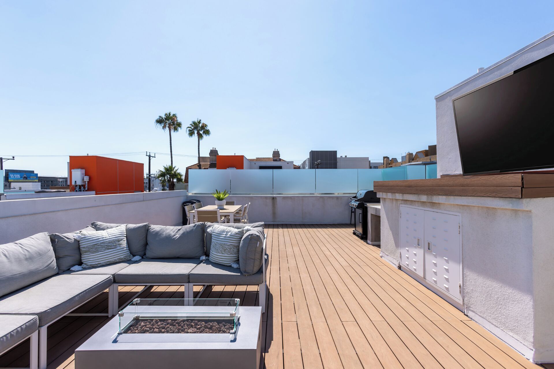 A rooftop patio with a sofa, a table, and a grill.