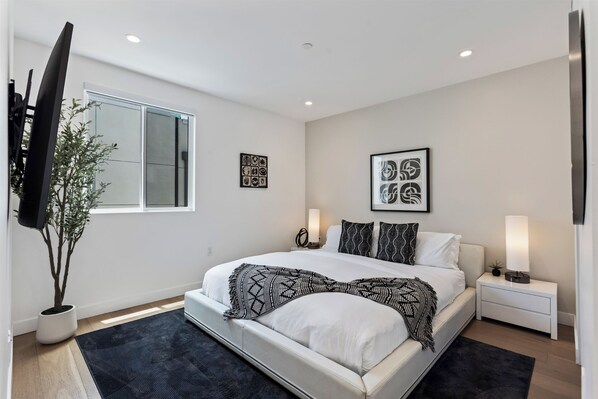 A modern bedroom with a large bed, bedside lamps, and artwork on the walls. - Casa Sycamore by Oraklus (Los Angeles)