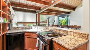 A kitchen with granite countertops, wooden cabinets, and a built-in stove. - Pet-friendly Oceanfront Getaway (Rockaway Beach)