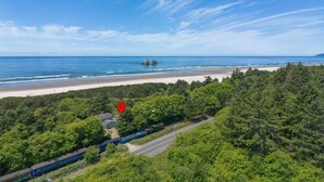 A coastal landscape with a beach, dense forest, and a train track. - Pet-friendly Oceanfront Getaway (Rockaway Beach)