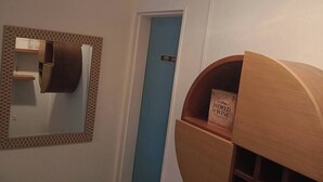 Ein Flur mit einer blauen Tür, einem Holzregal mit einem Buch mit dem Titel 'World of Wine' und einem an der Wand befestigten Toilettenpapierhalter.