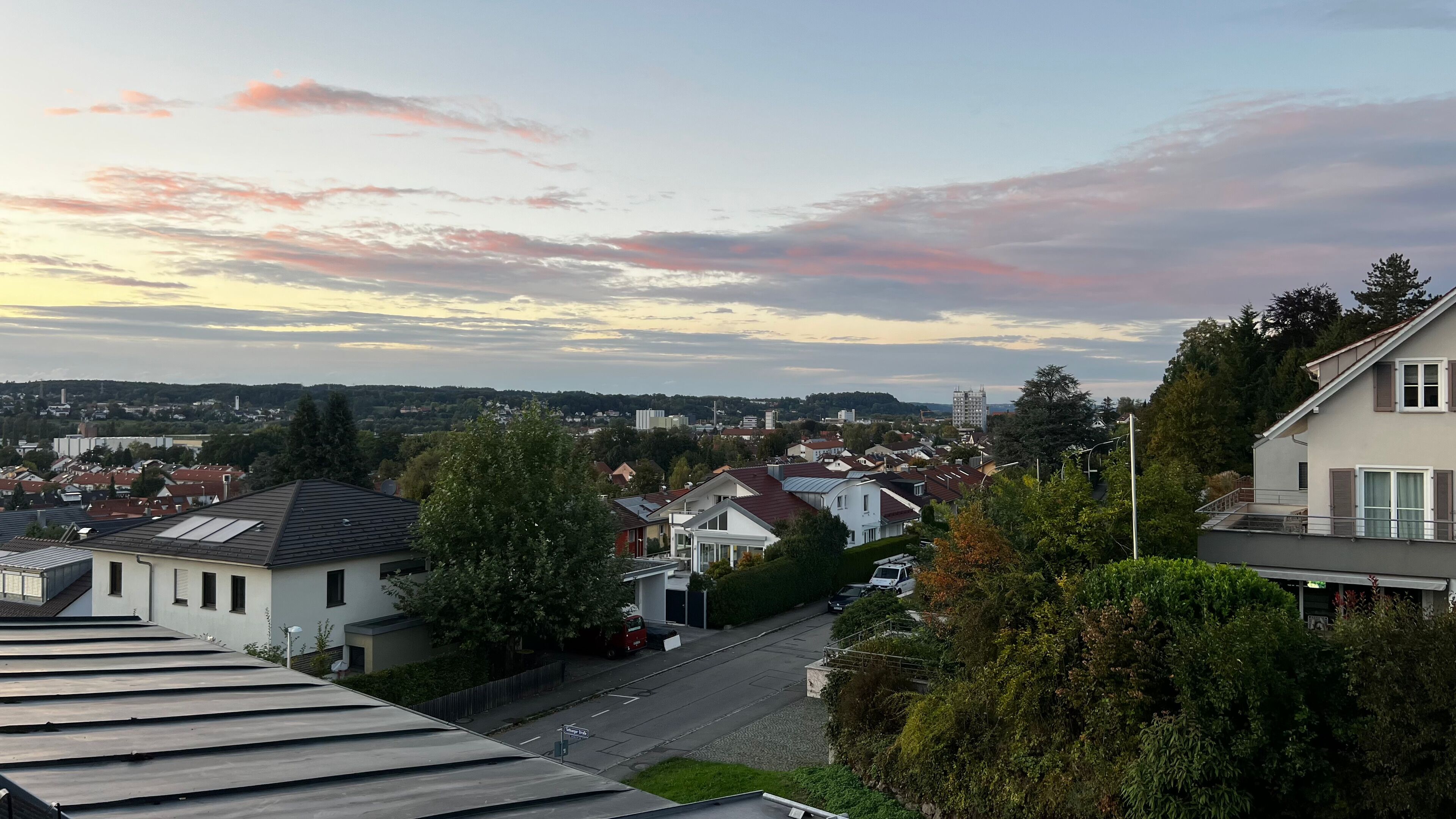 A residential area with houses, trees, and a clear sky.