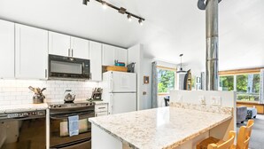 Een moderne keuken met witte kasten, een roestvrijstalen fornuis en een groot kookeiland met zitplaatsen.