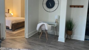 Ein Zimmer mit einem Bett, einem Schreibtisch, einem Stuhl, einer Uhr und einer Pflanze.