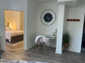 Une pièce comprenant un lit, un bureau, une horloge et une plante en pot.
