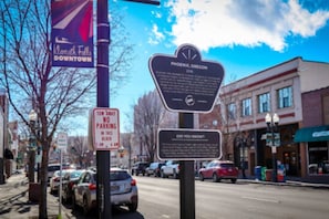 A street scene with a 'No Parking' sign, a 'Did You Know' informational sign, and a 'Phoenix, Oregon' historical marker. - 216 - The Governor’s Suite at The George (Klamath Falls)