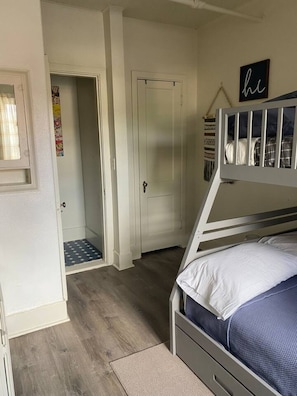 A bedroom with a bunk bed, a door, a small hallway, and a wall with a sign. - 216 - The Governor’s Suite at The George (Klamath Falls)