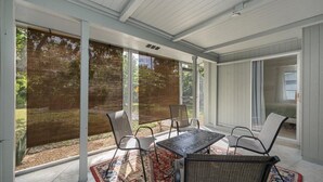 A covered patio with a table and chairs, large windows, and a view of the outdoors. - Costerra Naples 2BED (Naples)