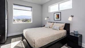 Un dormitorio con cama, dos lámparas de noche, un cuadro enmarco y una ventana con vistas.