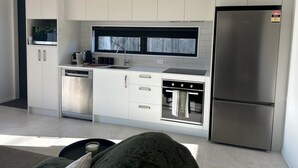 A modern kitchen with white cabinetry, a built-in oven, a stainless steel refrigerator, and a window above the sink. - 
The Park 
Modern,sun-filled two-bedroom townhouse, with free off-street parking (Christchurch)