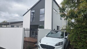 A modern two-story house with a white exterior and a black gate. - 
The Park 
Modern,sun-filled two-bedroom townhouse, with free off-street parking (Christchurch)