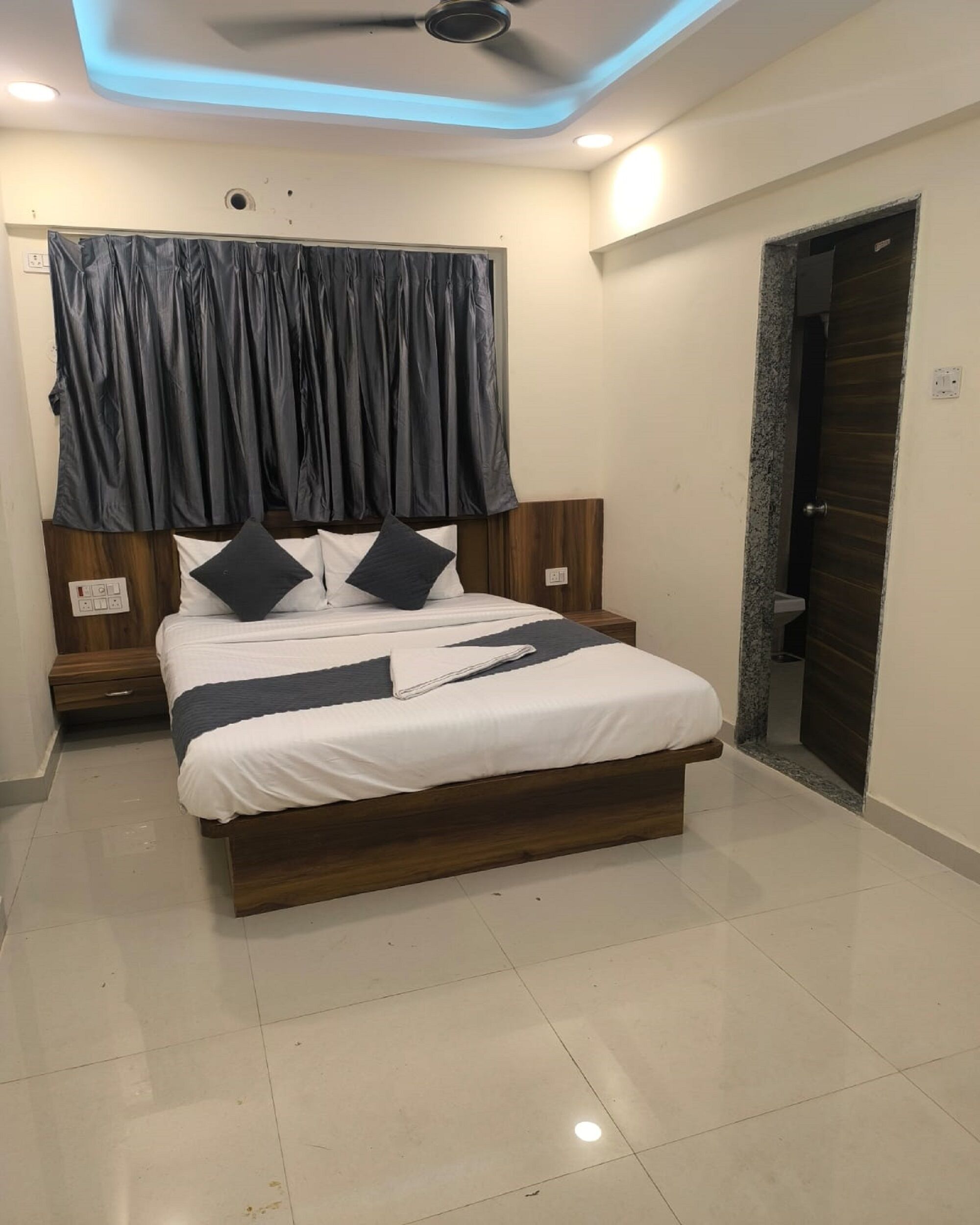 Un dormitorio moderno con cabecera de cama de madera, ropa de cama blanca y ventilador de techo.
