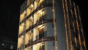 A multi-story building with balconies, illuminated by string lights, and a gated entrance. - Hotel Ratna Residency (Panvel)