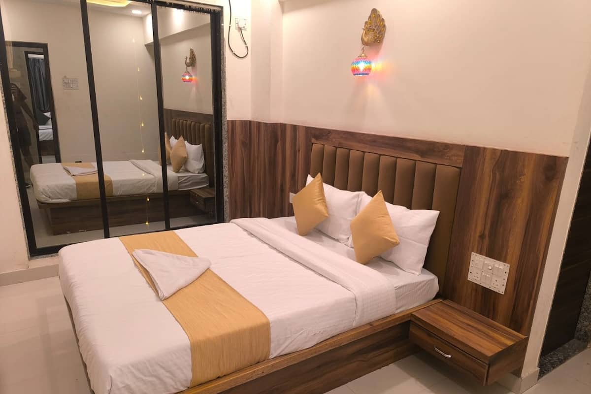 Hotellihuone, jossa on suuri sänky, puinen pääty, yöpöytä ja peili.