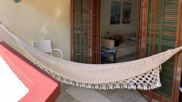 Una hamaca en una habitación soleada con vistas a un dormitorio a través de una puerta de cristal.