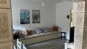 Una sala de estar con un conjunto de sofás, un televisor y obras de arte en la pared.