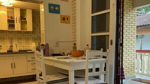 Una cocina con armarios blancos, una mesa de comedor con sillas y una ventana con vistas al exterior.