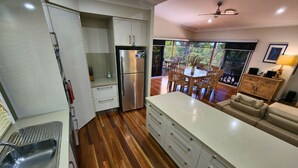 Une cuisine moderne dotée d’un réfrigérateur en acier inoxydable, d’un plancher en bois et d’un coin repas avec une table et des chaises.