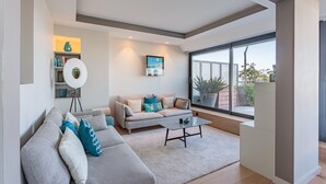 Een moderne woonkamer met een bank, salontafel en een groot raam met uitzicht op de omgeving.
