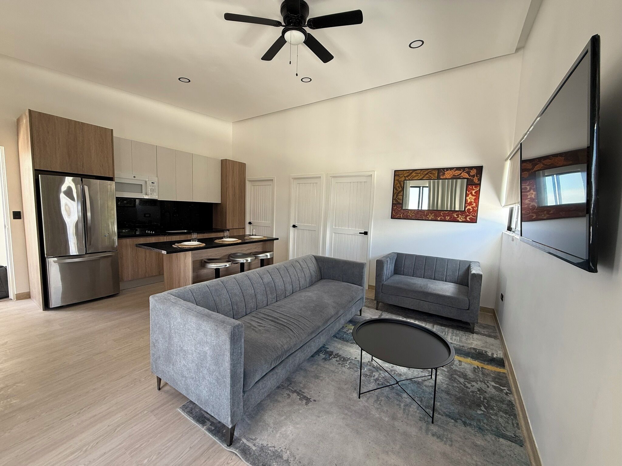 Un salon moderne avec un canapé gris, une petite table ronde et un ventilateur de plafond.