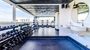 Une salle de sport équipée de matériel d’exercice, d’un miroir et d’une grande fenêtre.