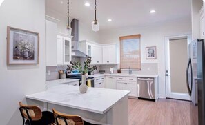 Una cocina moderna con armarios blancos, una isla central e iluminación colgante.